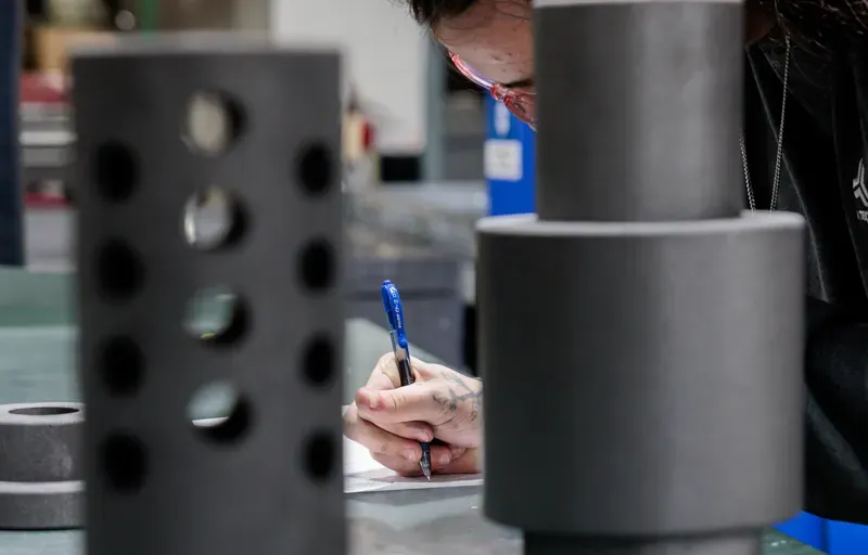 Engineer taking notes beside machined composite parts