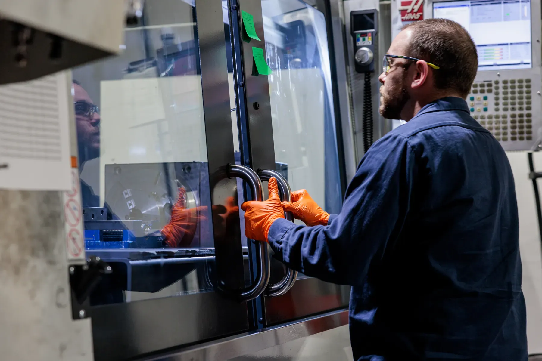 FMI technician in orange gloves opening the door of a production machine