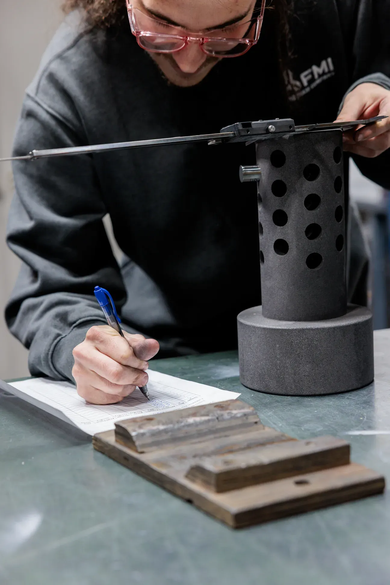 FMI team member writing notes beside a machined composite part