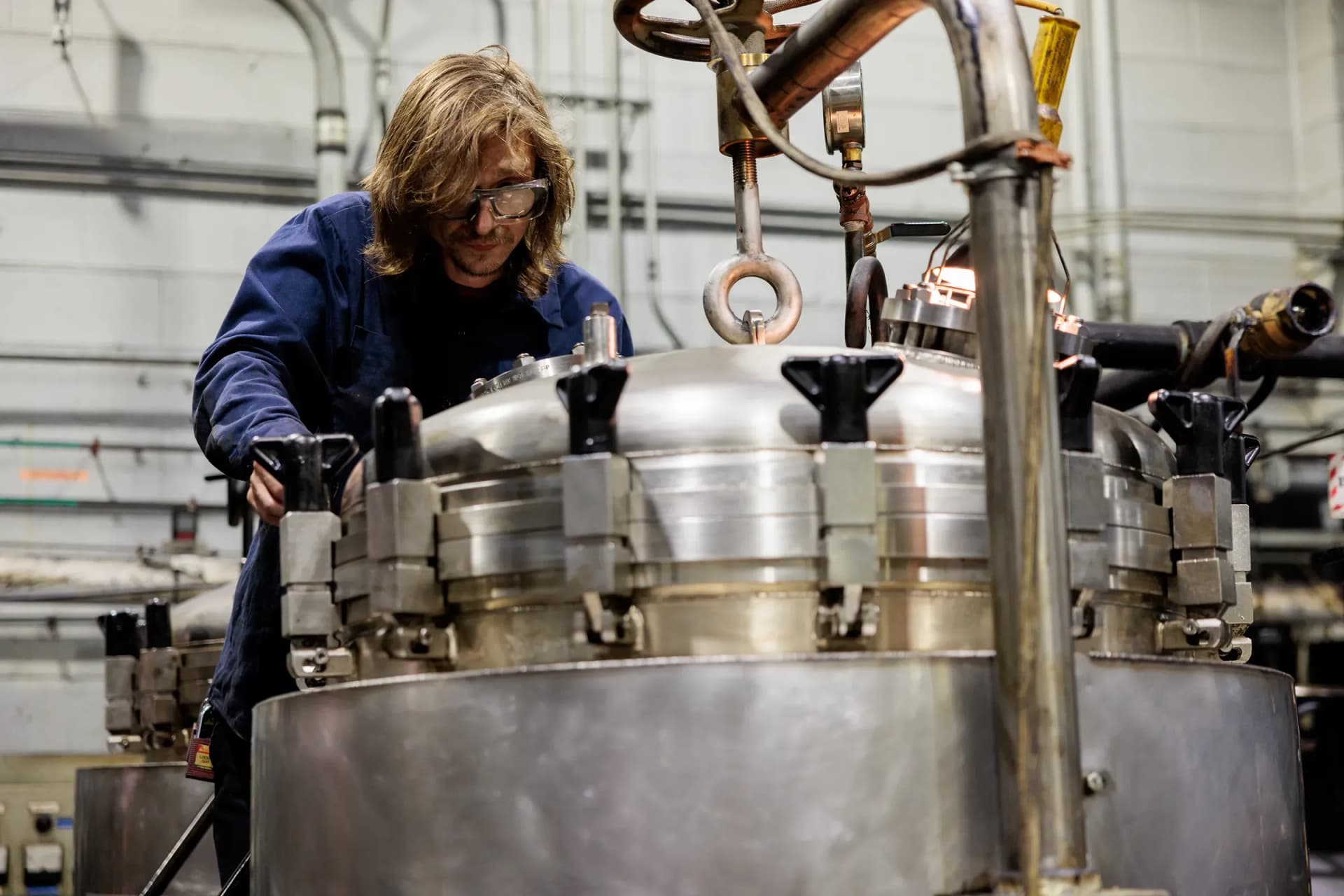 FMI technician in safety glasses working on a large metal assembly